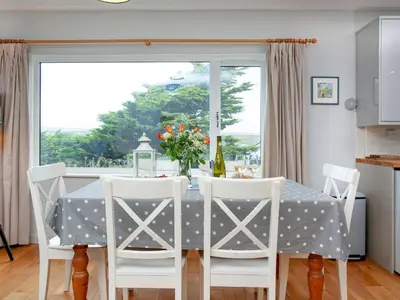 a dining room with a table and chairs and a window at Semybadazee in Poundstock