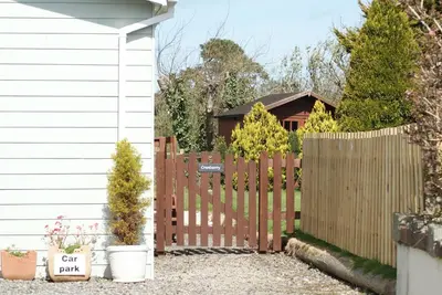 a wooden fence in front of a house at Family friendly rural lodge in Truro