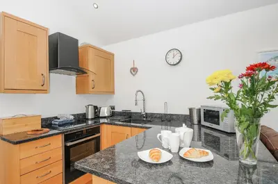 a kitchen with a counter top with a vase of flowers at Pol Glas Cabin in Helston