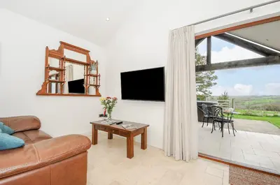a living room with a couch and a television at Pol Glas Cabin in Helston