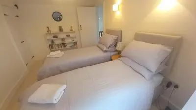 two beds in a small room with white sheets at Quayside in Porthscatho