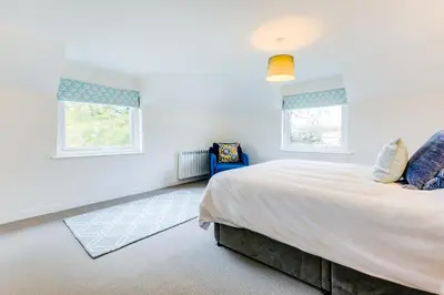a bedroom with a large bed and two windows at Goose Cottage - within the Helland Barton Farm collection in Delabole