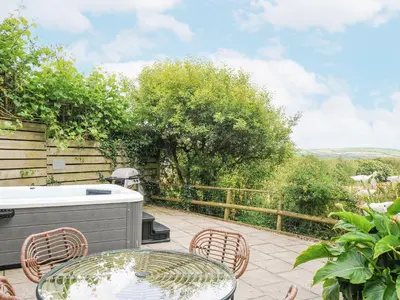 a patio with a table and chairs and a grill at Goose Cottage - within the Helland Barton Farm collection in Delabole