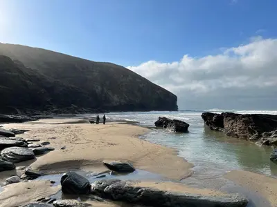 two people standing on a beach near the ocean at Courtyard Cottage - within the Helland Barton Farm collection in Delabole