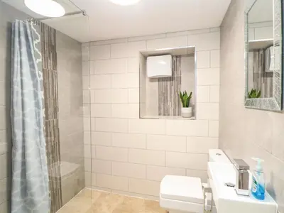 a white bathroom with a shower and a sink at Ty Bryn in Marazion