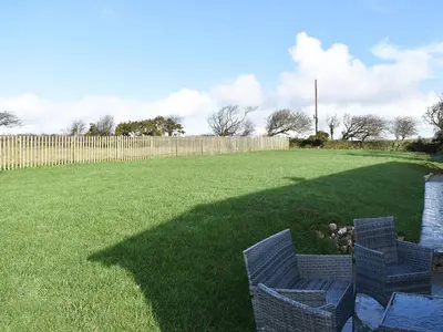 two chairs sitting in a yard with a fence at Four Burrows Bungalow in Chacewater