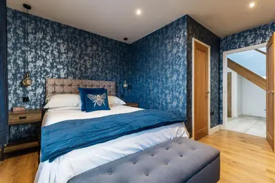 a bedroom with blue wallpaper and a bed with a blue pillow at Porthleven View in Porthleven