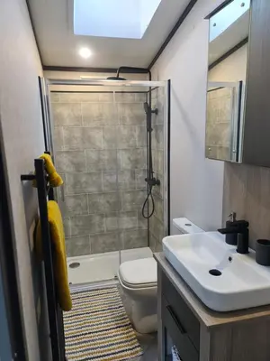 a bathroom with a shower and a toilet and a sink at Mawgan Pads Lazy Days Lodge in Mawgan Porth