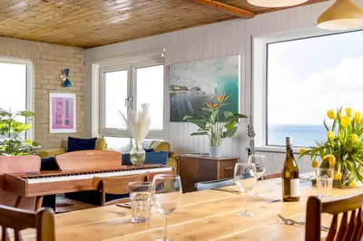 a dining room with a table with wine glasses at Sunset Beach House Porthleven in Porthleven