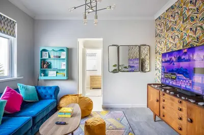 a living room with a blue couch and a tv at Sunset Beach House Porthleven in Porthleven