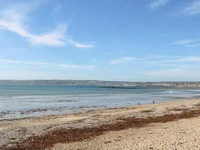 a beach with the ocean and buildings in the background at Tregonning Lodge in Helston