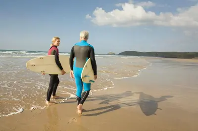 two men walking on the beach with their surfboards at Central Falmouth Flat with Free Parking in Falmouth
