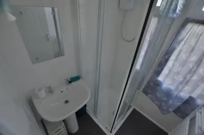 a white bathroom with a shower and a sink at B47 Neptune, Riviere Towans in Hayle