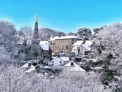 a town covered in snow with a building and a church at Chy Cos. South facing lodge with balcony & views. in St. Agnes