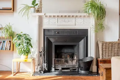 a fireplace in a living room with two potted plants at Treetops - Characterful flat with parking, close to beach in Falmouth