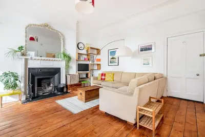 a living room with a couch and a fireplace at Treetops - Characterful flat with parking, close to beach in Falmouth