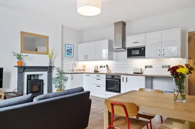 a kitchen and living room with a couch and a table at Pendennis - Bright Victorian flat, sea views & close to beach in Falmouth
