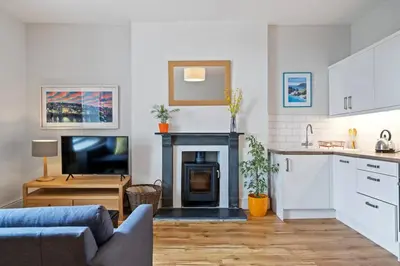 a kitchen and living room with a couch and a fireplace at Pendennis - Bright Victorian flat, sea views & close to beach in Falmouth