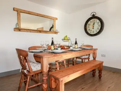 a table with wine glasses and a clock on the wall at Bimbling Cottage in Redruth