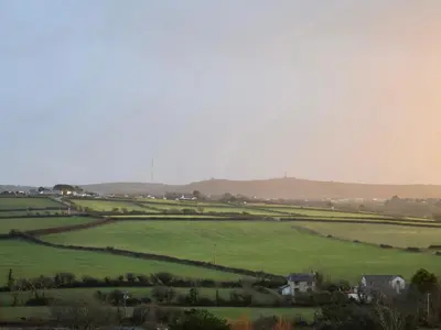 a large green field with houses in the distance at Bimbling Cottage in Redruth
