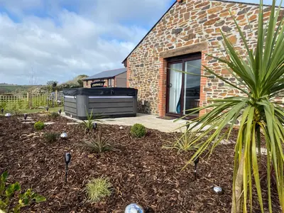 a garden with a brick house and a palm tree at Bimbling Cottage in Redruth