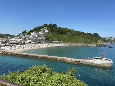 a group of people on a beach with a boat in the water at Linhay at East Trenean Farm -Luxury retreat for 2 with stunning rural views, private hot tub and EV charging in Looe