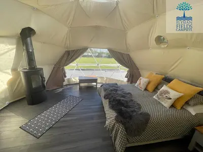a living room with a couch in a tent at Glamping Dome Elysian Fields in Helston