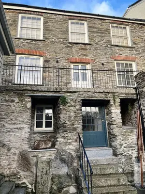 an old stone building with a blue door and stairs at Sandpiper in Fowey