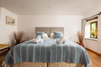 a bedroom with a bed with a blue and white blanket at East Trenean Farm Cottages -4 Luxury Cornish Cottages sleeping 20 with hot tubs, private gardens, rural views and EV facilities in Looe