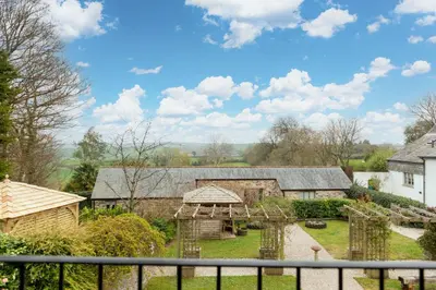 a view of a house with a fence at Threshing Barn at East Trenean Farm -Stunning Cornish Cottage sleeping 6 with hot tub, private garden, rural views and EV facilities in East Looe