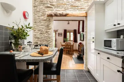 a kitchen and dining room with a table in a kitchen at Water Mill at East Trenean Farm -Luxury Cornish Cottage sleeping 4 with hot tub, private garden, rural views and EV facilities in East Looe