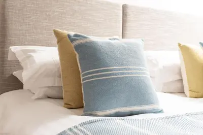 a blue pillow on a bed with white pillows at Water Mill at East Trenean Farm -Luxury Cornish Cottage sleeping 4 with hot tub, private garden, rural views and EV facilities in East Looe
