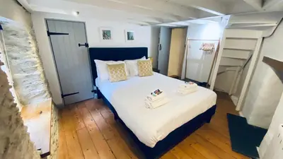 a bedroom with a bed with two towels on it at SPINDRIFT is A Beautiful Newly Refurbished THREE BEDROOM Private Family House located on the OLD HARBOUR and the COASTAL PATH in the Heart of Beautiful POLPERRO in Polperro