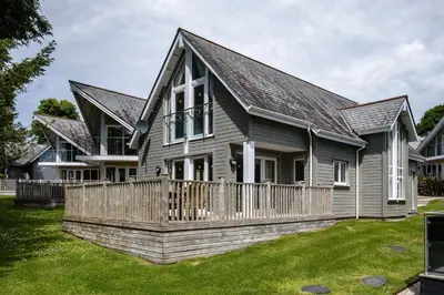 a house with a wooden fence in the yard at Trewhiddle Retreat V27 by Together Travel - Luxury 3-Bedroom Villa in St Austell