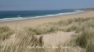 a sandy beach with grass and the ocean at 19 Strawberry Hill, Tolroy Manor in Hayle