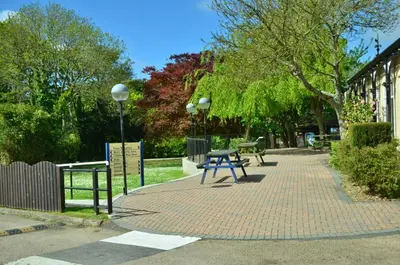 a park with a picnic table on a brick sidewalk at 25 Tudor Court, Tolroy Manor in Hayle