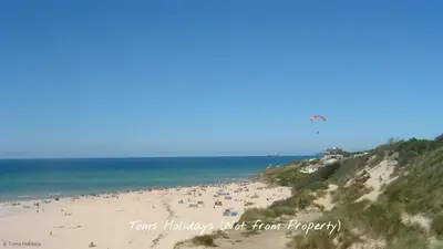 a group of people on a beach flying a kite at D29 Westbourne, Riviere Towans in Hayle