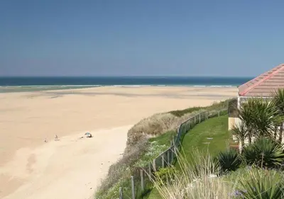 a view of a beach with a fence and the ocean at D38 Miramar, Riviere Towans in Hayle