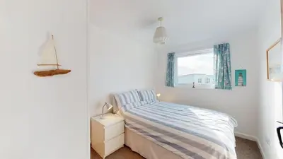 a white bedroom with a bed and a window at D22 Sandelite, Riviere Towans in Hayle