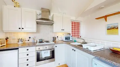 a kitchen with white cabinets and a stove top oven at D22 Sandelite, Riviere Towans in Hayle