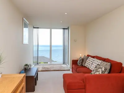 a living room with a red couch and a large window at Ocean View in Carbis Bay