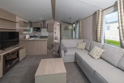 a living room with a couch and a kitchen at Luxury Holiday Home Sleeps 6 Pet Friendly in St Austell