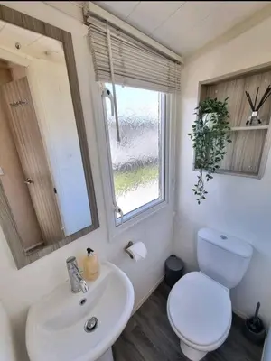 a bathroom with a toilet and a sink and a window at Seven Sunsets, Padstow in Padstow