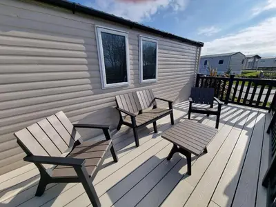 a deck with two benches and a table and a building at Seven Sunsets, Padstow in Padstow