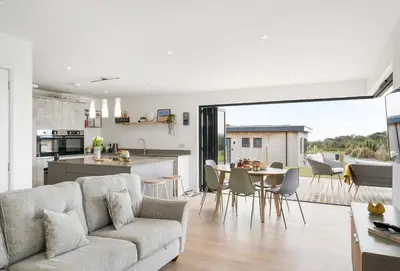 a living room and kitchen with a couch and a table at Poppyfields in Germoe
