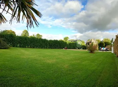 a large lawn with a gazebo in a yard at Romantic Retreat - Luxury Shepherds Hut + Hot Tub! in Camborne
