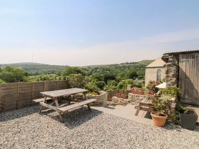 a picnic table on a gravel patio with a view at Small Barn in Liskeard