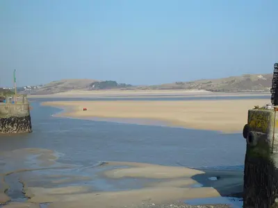 a body of water with a beach and a pier at Small Barn in Liskeard