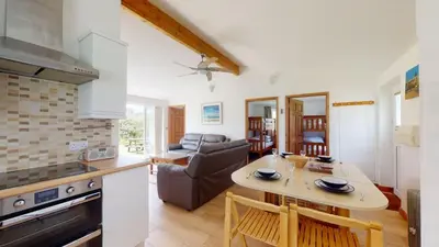 a kitchen and living room with a table and a couch at F26 Porthia, Riviere Towans in Hayle