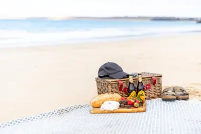 a picnic basket on the beach with shoes and sandals at Carbis Bay - Luxury 3 Bed Penthouse Apartment with Sea Views Parking Sauna Balcony in Carbis Bay